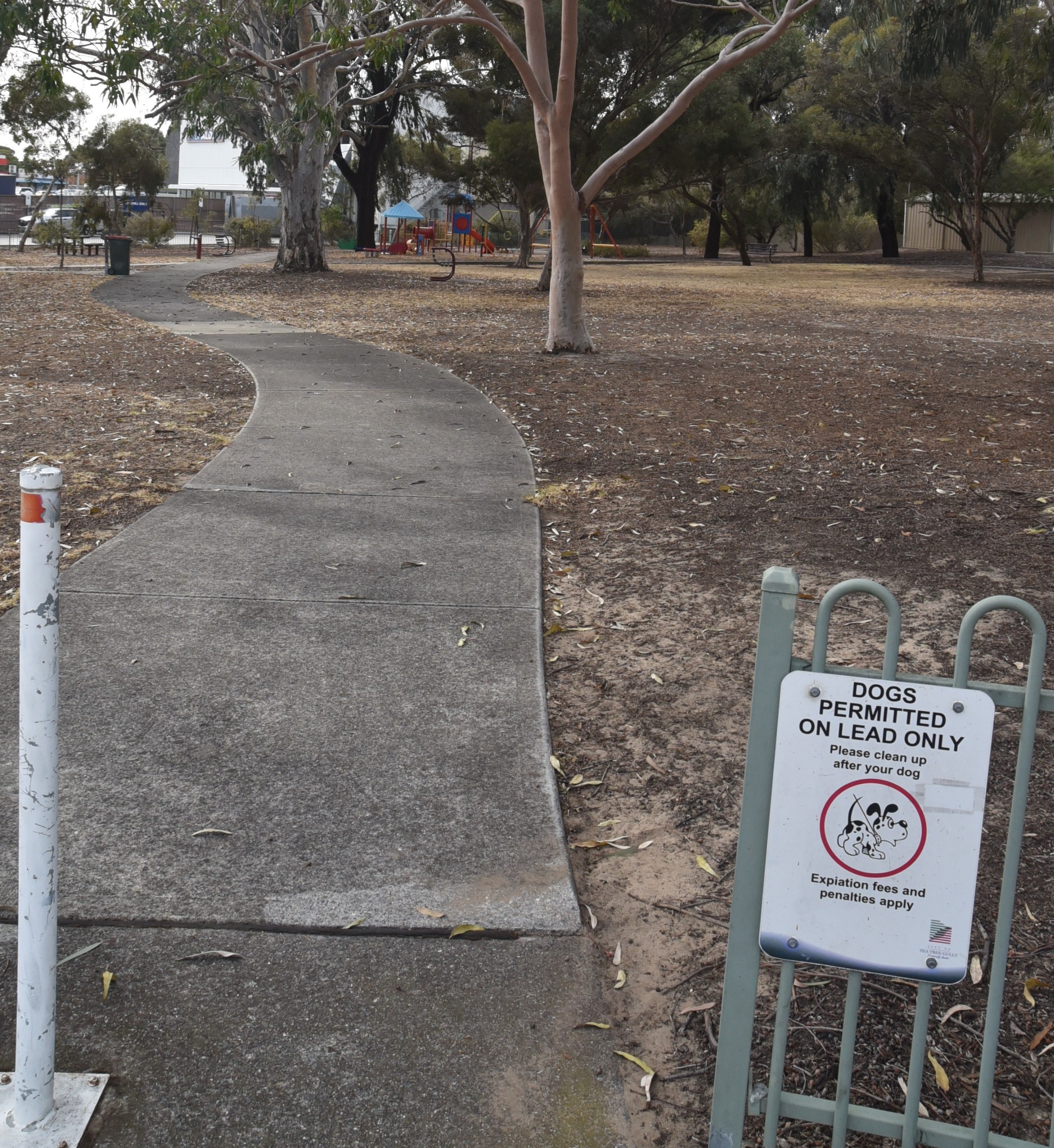 Concrete path leading into Whinnen Reserve. There is some fence to the right hand side with a sign saying dogs permitted on a lead only