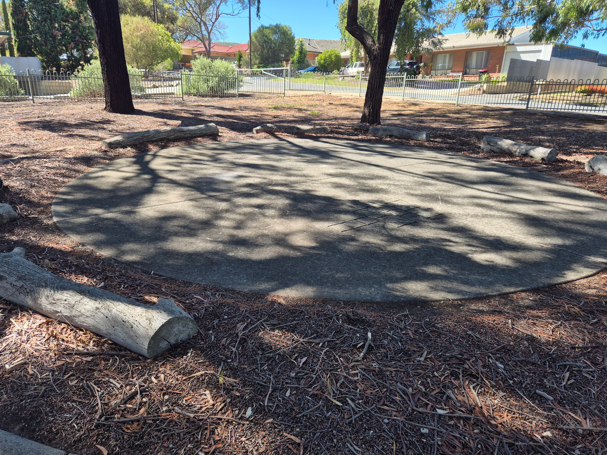 Circular concrete pad under trees surrounded by log seating