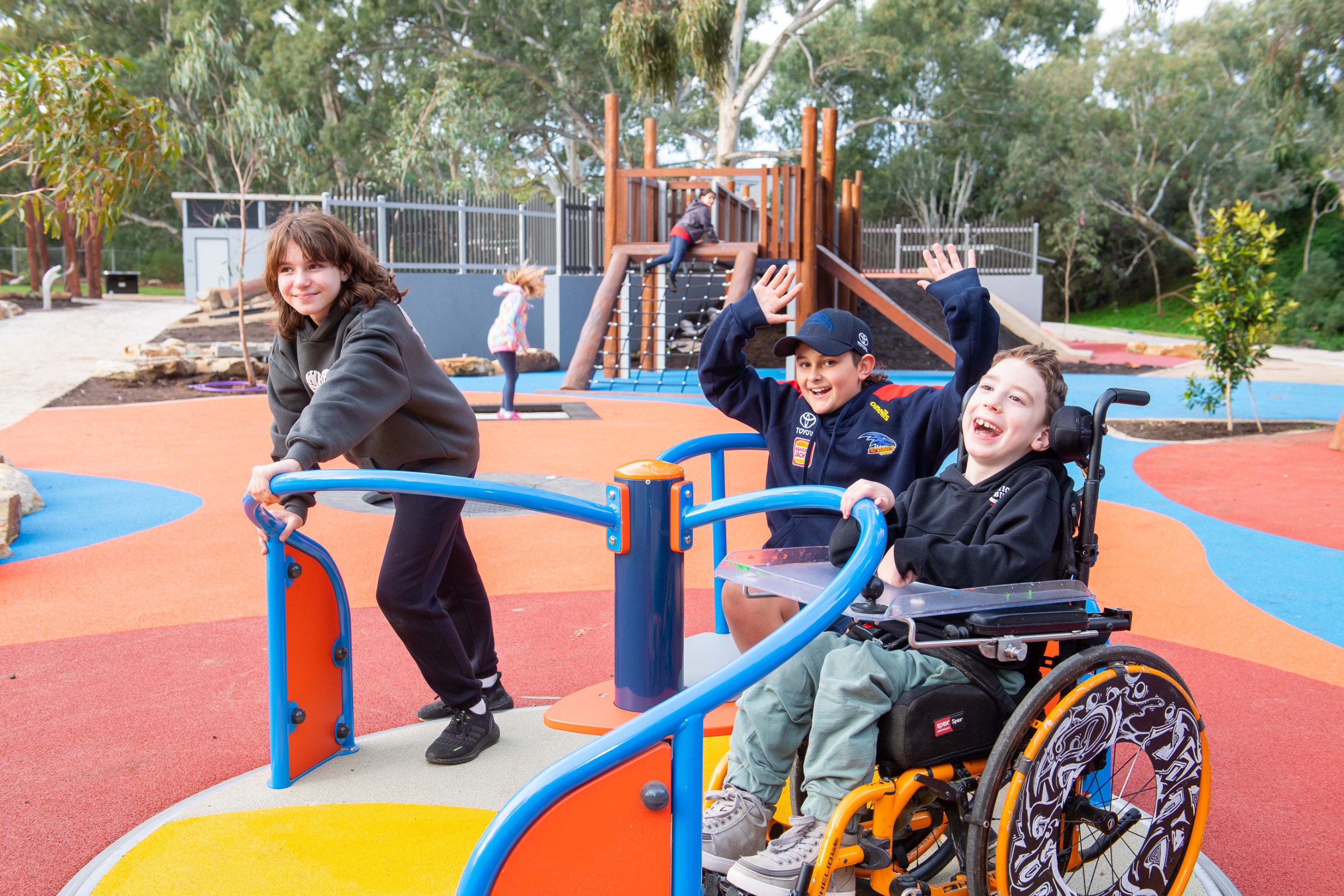 A child in wheelchair and two other children using a spinning carousel